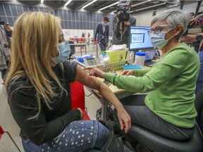 Annie Dufour, media relations person for the CIUSSS Centre-Sud sits for a simulated vaccination from veterinarian Christine Vézina during a tour of the mass vaccination clinic at the Palais des congrès on Monday.