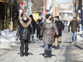 People wear face masks as they walk along a street in Montreal, Sunday, January 31, 2021.