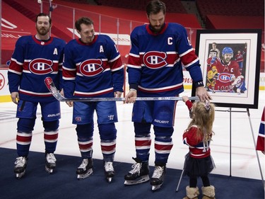 Montreal Canadiens defenseman Shea Weber (6) lets his youngest daughter touch his silver stick presented by Montreal Canadiens left wing Paul Byron (41) and Montreal Canadiens right wing Brendan Gallagher (11) to mark his 1000th NHL game, at the Bell Centre in Montreal on Thursday, Feb. 4, 2021.