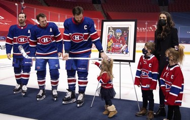 Montreal Canadiens defenseman Shea Weber (6) lets his youngest daughter touch his silver stick presented by Montreal Canadiens left wing Paul Byron (41) and Montreal Canadiens right wing Brendan Gallagher (11) to mark his 1000th NHL game, at the Bell Centre in Montreal on Thursday, Feb. 4, 2021.