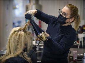 Lynda Larocque styles Ginette Primeau's hair at her shop in Montreal West on Monday Feb. 8, 2021. She had 130 phone messages requesting appointments on the first day since the Legault government relaxed certain COVID-19 restrictions.