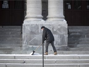 Andre Dube shovels the light snow that fell on the steps of St Jean Baptiste church on Rachel St. on Feb. 9, 2021