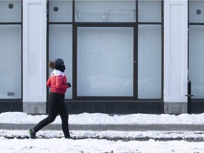 A woman runs past a closed shop in Montreal Feb. 9, 2021 during the COVID-19 pandemic.