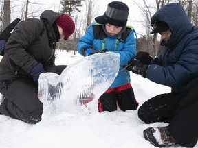 Laudalina Galdamez, left, and Douglas Galdamez help their son Ezequiel complete a whale-shaped ice sculpture, during the St-Lazare winter caravan held at Westwood Junior park on Saturday, Feb. 6, 2021.
