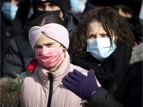 Salema holds a rose and her 11-year-old daughter, Dania, as they listen to speakers during a vigil in Montreal on Feb. 14, 2021, for Meriem Boundaoui, who was a 15-year-old girl from the South Shore who was shot in the head early in the evening of Feb. 7 while seated in a car that was struck by several bullets on Valdombre St., near Jean Talon St., in St-Léonard.