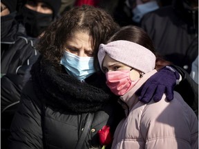 Salema holds a rose and her 11-year-old daughter, Dania, as they listen to speakers during a vigil for Meriem Boundaoui in Montreal Feb. 14, 2021.