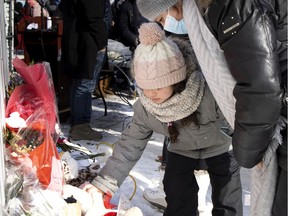 A young child lays a stuffed animal down at a shrine to shooting victim Meriem Boundaoui, during a vigil in Montreal on Sunday, Feb. 14, 2021.