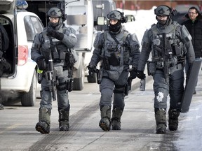 Montreal police SWAT team members return to their armoured truck after an intervention in the DDO district of Montreal on Saturday, February 13, 2021.