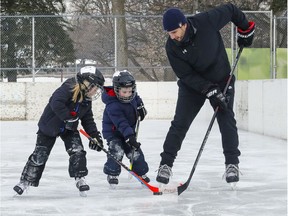 With the minor hockey season still in limbo due to the pandemic, Bruno D'Amico skates with sons Jack, left, and Ben on the outdoor rink at Ovide Park in Pointe-Claire on Monday.