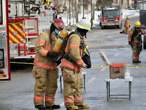 A firefighter has his oxygen tank changed outside an apartment building on Cote-St-Luc Rd. in Montreal Thursday February 18, 2021 after a fire in the building caused traffic problems, power outages and the closing of a school across the street.