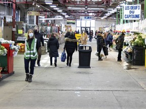 A COVID-19 compliance staffer patrols the retail areas of Jean-Talon Market in Montreal.