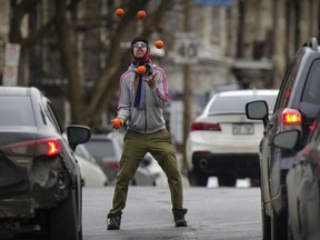 Gabriel Boileau juggles for spare change at the corner of Atwater Ave. and St-Antoine St. in Montreal Wednesday February 24, 2021.  In addition to juggling he does magic and is using the juggling to fund his dream of performing in Las Vegas.