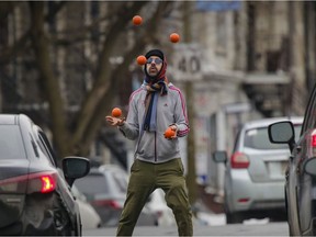 Gabriel Boileau juggles for spare change at the corner of Atwater Ave. and St-Antoine St. in Montreal Wednesday February 24, 2021.  In addition to juggling he does magic and is using the juggling to fund his dream of performing in Las Vegas.