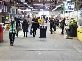 A COVID-19 compliance staffer, left, patrols the retail areas of Jean-Talon Market in Montreal on Thursday, February 18, 2021.