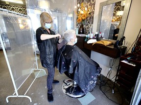 Heather Macbeth styles Geraldine Tatarelli’s hair at Mastro Coiffure in Montreal Feb. 8, 2021, the first day of reopening of stores, hair salons, libraries and museums after the Quebec government loosened some COVID-19 restrictions.