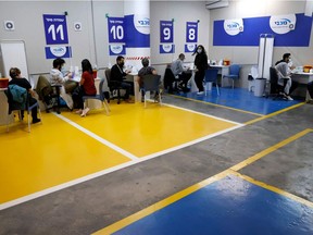 Health workers of the Maccabi Health vaccination centre administer doses of the Pfizer-BioNtech COVID-19 coronavirus vaccine inside the parking lot of the Givatayim mall in Israel's Mediterranean coastal city of Tel Aviv on January 26, 2021.