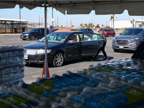 Volunteers hand out cases of water bottles to Galveston residence at the Schlitterbahn Waterpark parking lot on Friday, Feb. 19, 202,1 in Galveston, Tex. A fierce and deadly winter storm that wreaked havoc in the southern and central U.S. and blanketed the East Coast in snow was forecast Friday to start tapering off.