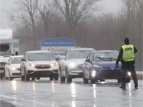 Sûreté du Québec officers stop motorists at a checkpoint near the Ontario border on March 29, 2020, during the first wave of the COVID-19 pandemic.