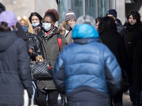 People wear face masks as they walk along a street in Montreal, Sunday, February 21, 2021,.