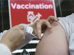 A woman receives her COVID-19 vaccine at a vaccination clinic in Montreal's Olympic Stadium on Tuesday, Feb. 23, 2021.