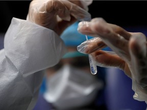 A medical worker holds a test tube after administering a nasal swab to a patient at a COVID-19 testing centre in France.