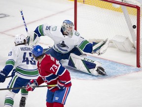 Canadiens' Tyler Toffoli deflects the puck past Canucks goaltender Thatcher Demko while defenceman Quinn Hughes watches helplessly Tuesday night at the Bell Centre.