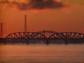 The sky is bathed in warm light behind the Mercier Bridge and the neighbouring rail bridge at sunrise in Montreal Monday February 1, 2021.