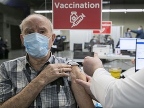 Emilien Mainville receives his first shot of COVID-19 vaccine by nurse Chad Gherbaz at Olympic stadium on Monday March 1, 2021 during the first day of mass vaccination in Montreal.