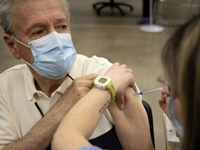 Jean-Pierre Bourbonnais receives his COVID-19 vaccination from Roxane Valcourt at the Palais des congres in Montreal March 1, 2021.