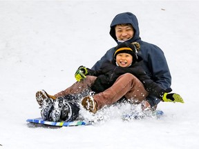 Ethan Xu and son Ethan Jr. spin sideways while sledding in Westmount Park.