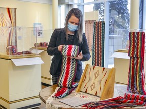 Cultural officer Sara Giguère folds a sash at the Dorval Museum of Local History and Heritage's new exhibition The Arrow Sash at Your Fingertips. The museum reopened to the public on Wednesday, but reservations are required due to COVID-19.