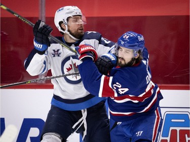 Montreal Canadiens left wing Phillip Danault grimaces as he takes a hit from Winnipeg Jets right wing Blake Wheeler in the third period in Montreal on Thursday, March 4, 2021.