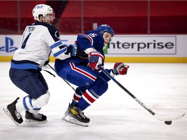 Montreal Canadiens centre Jesperi Kotkaniemi tries to keep his stick on an airborne puck as Winnipeg Jets defenseman Neal Pionk tries to knock him off the play during second period in Montreal on Thursday, March 4, 2021.