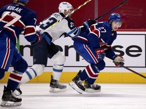 Canadiens defenceman Alexander Romanov (27) reacts as Winnipeg Jets centre Trevor Lewis (23) follows close behind during NHL action in Montreal on March 4, 2021.