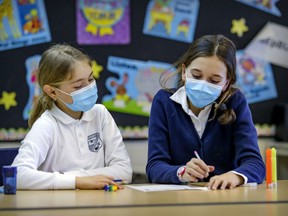 Grade 4 students Mathilde Benjamin, left, and Béatrice O'Doherty wear masks while working together in class at John Caboto Academy in the Ahuntsic district of Montreal Monday March 8, 2021. It became mandatory that day for elementary school students from grades 1 to 4 to wear masks during class.