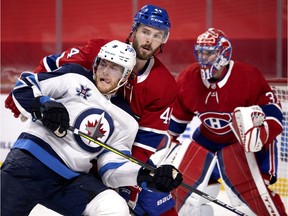 Winnipeg Jets centre Andrew Copp (9) leans into Montreal Canadiens defenseman Joel Edmundson (44) as Montreal Canadiens goaltender Carey Price (31) follows the play during NHL action in Montreal on Saturday, March 6, 2021.