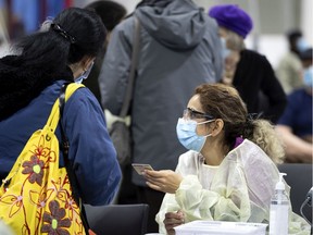 A health care worker checks a client's identity before administering a Covid-19 vaccination at the Bill Durnan Arena in Montreal on Wednesday, March 10, 2021.
