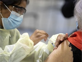 A heath care worker administers a COVID-19 vaccination at the Bill Durnan Arena in Notre-Dame-de-Grâce on Wednesday, March 10, 2021.