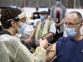 A healthcare worker administers the Covid-19 vaccination to David Hood, 72, at a new clinic inside the Bill Durnan Arena in Montreal on Wednesday, March 10, 2021.