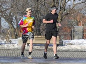 Dylan Desmarais, left, and Andrew Robinson cross Park Ave. while running in Montreal Wednesday March 10, 2021.