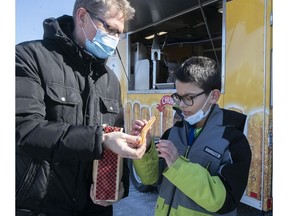 Calvin Vanden Bos hands over a hot churro to his son Jaiden, outside the Baie-D'Urfé Provigo on Sunday. Provigo will donate its portion of the Cabane à Chichis Churros food truck sales to local Scouts and Guides. The food truck is set to return to this Provigo site from Thursday to Sunday.