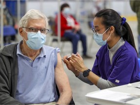 Podiatrist Jennifer Vuong-Nguyen vaccinates Martin Chance at the mass COVID-19 vaccination clinic at Bob Birnie Arena in the Pointe Claire suburb of Montreal Monday March 8, 2021.