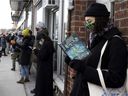 Trynne Delaney reads while in a long line on St-Viateur St. during a 