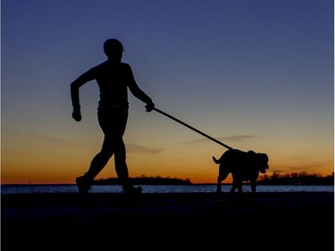 A woman runs with her dog at sunset on the waterfront in Lachine.