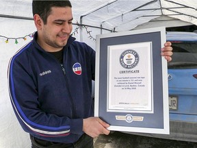 Daniel Wassef looks at his Guinness World Record certificate for most soccer toe taps in a minute, outside his house in Laval, north of Montreal Thursday March 18, 2021.