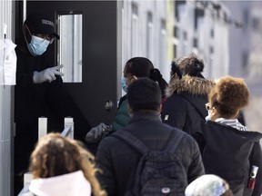A security guard gives instructions to people waiting in line for COVID-19 testing at the Jewish General Hospital in Montreal, on Tuesday, March 23, 2021.