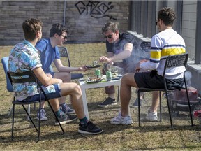Roommates, left to right, Alexandre, Benjamin, Benoit and Karim have a barbecue in Jeanne-Mance Park on Tuesday, March 23, 2021.