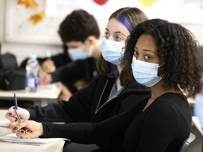 Grade 11 students Sophie Wugalter, left to right, and Elysia Ross listen to an online presentation as part of Anti-Racism Week at John Rennie High School in Pointe-Claire on Wednesday.