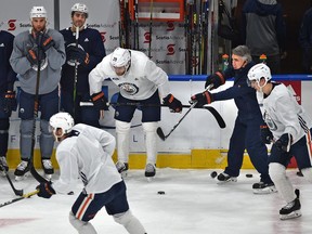 Oilers head coach Dave Tippett, right, fires the puck toward the net during practice drills last month.