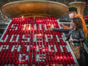 Iren Montecalvo and Erwin Intong light votive candles at Saint Joseph's Oratory after it reopened in Montreal on Friday, March 26, 2021.